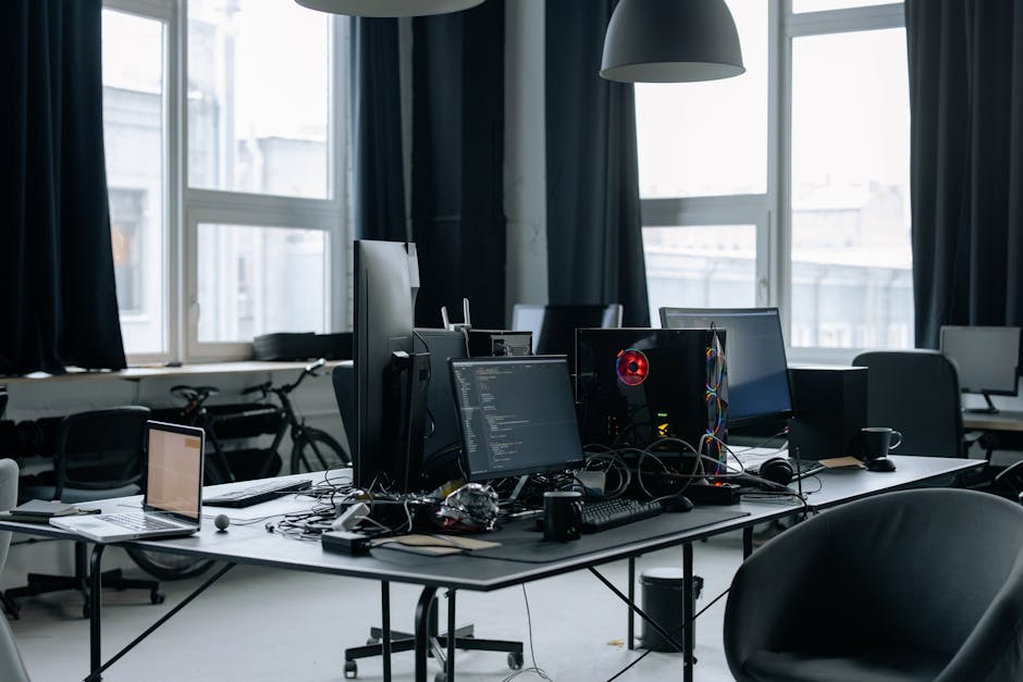 Contemporary workspace featuring computers, coding screens, and office essentials in a tech environment.